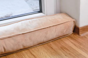 Draft Excluder Lying In Front Of Door To Keep Out Cold Air A