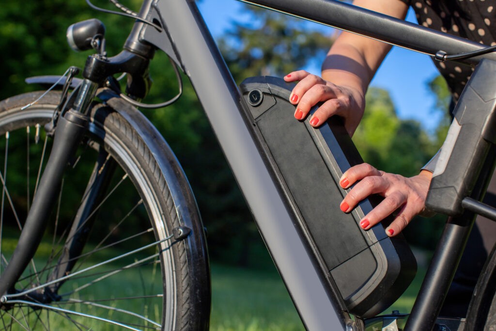 Detail Of Woman Holding An Electric Bike Battery Mounted On Frame